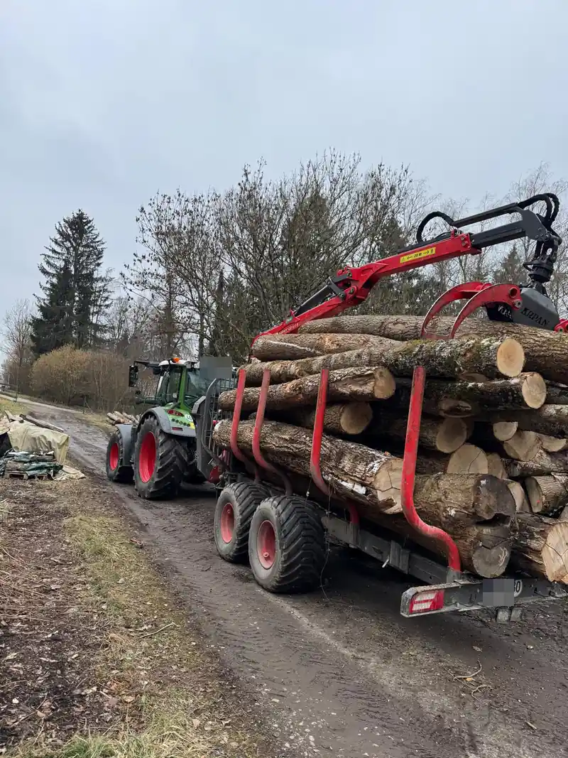Schlepper mit voll beladenem Rückewagen und Kran auf dem Waldweg